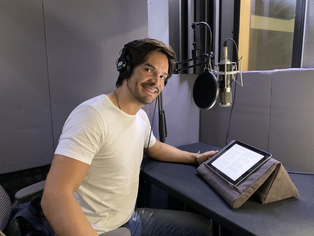 Narrator seated at the microphone in a Blacknoise Audio booth